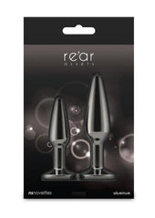 Packaging of 'rear assets' with two black butt plugs on a dark background.