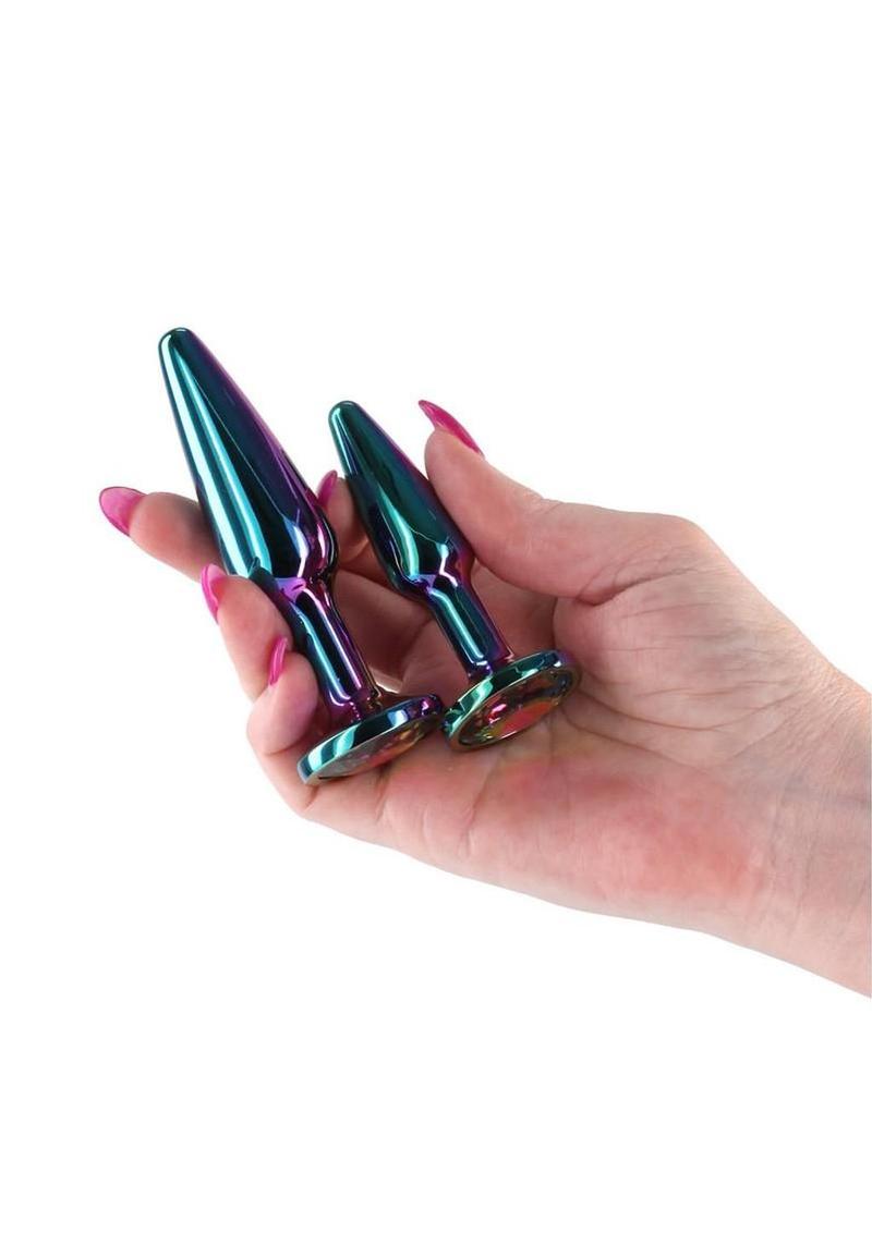 Hand holding three metallic butt plugs with a white background